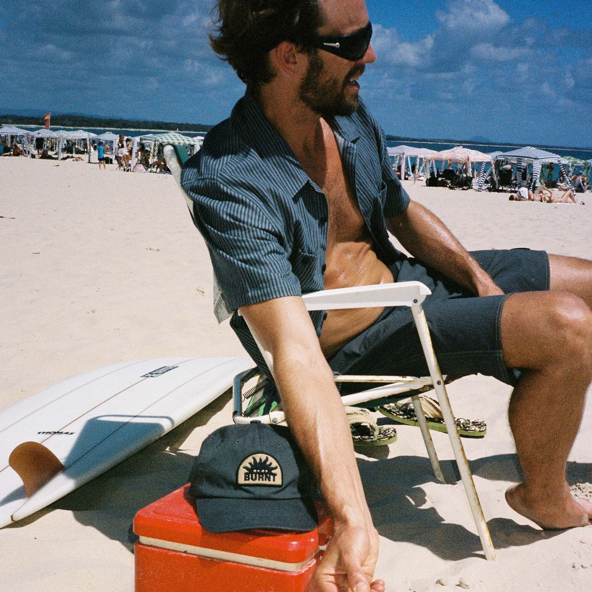 Sommerliche Abenteuerstimmung mit einem stylischen Hut und einer Sonnenbrille aus der Burnt Collection, perfekt für Freizeit und Urlaub.