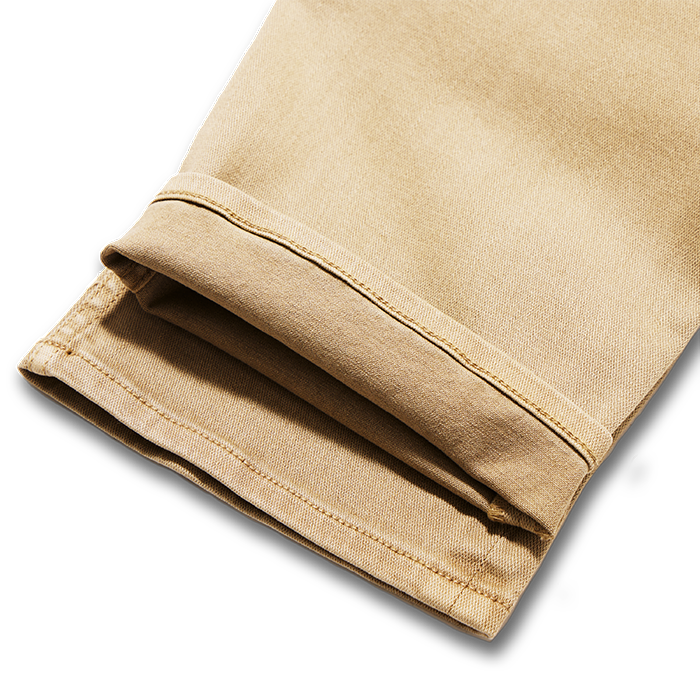 Assortment of Roark's adventure-ready pants including khaki, denim, and cargo styles, showcasing button details and functional pockets for travel and outdoor activities.