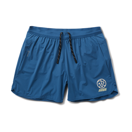 Mann in Roark-Aktivbekleidung, einschließlich Boardshorts im Bermuda-Stil und Aktivshirt, bei der Erkundung der zerklüfteten Küste.