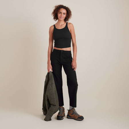 Das Model trägt ein schwarzes, geripptes Tank-Top zu einer lässigen Hose und unterstreicht damit die vielseitige und schlichte, minimalistische Mode.